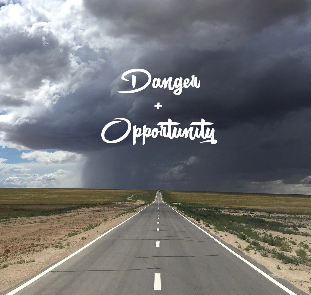 An empty road running into a storm, with the words Danger + Opportunity